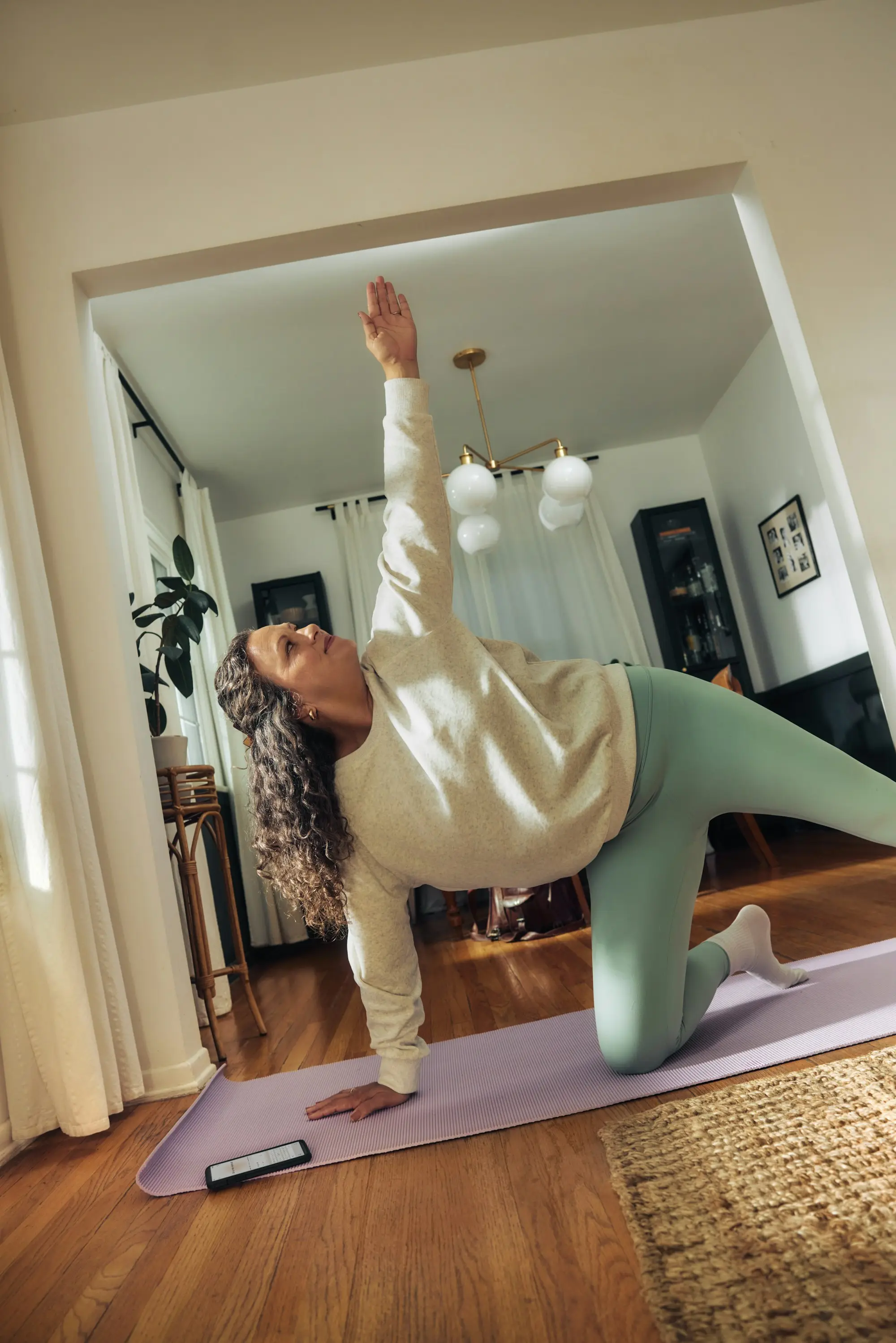 Femme pratiquant le Pilates sur un tapis dans son salon